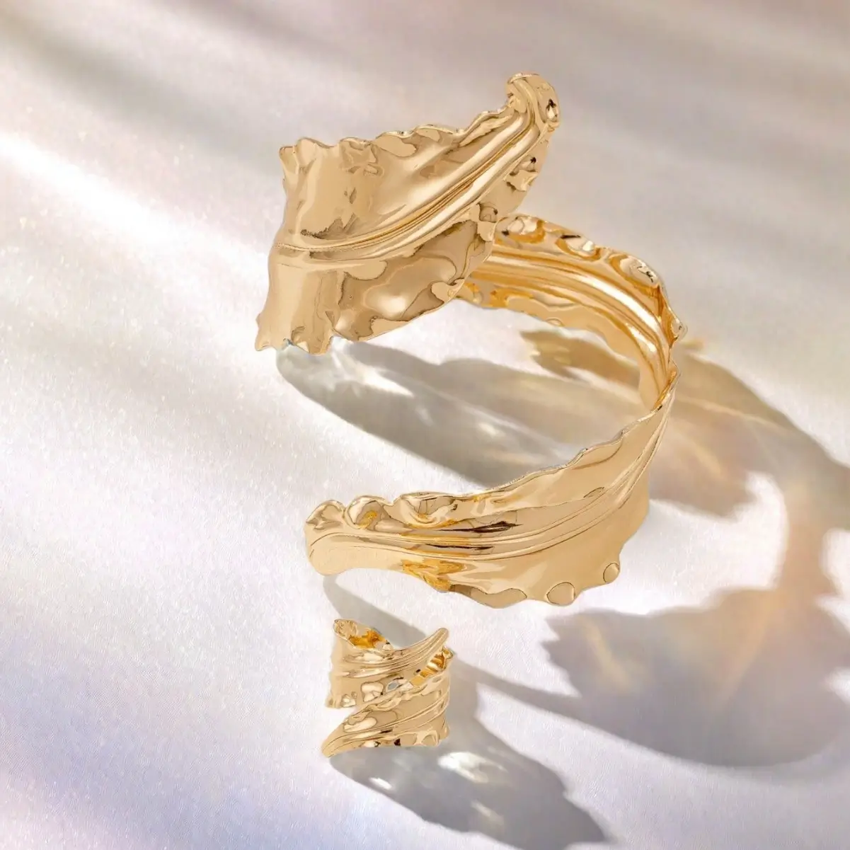 Sculptural molten gold cuff bracelet with matching adjustable ring on model's hand